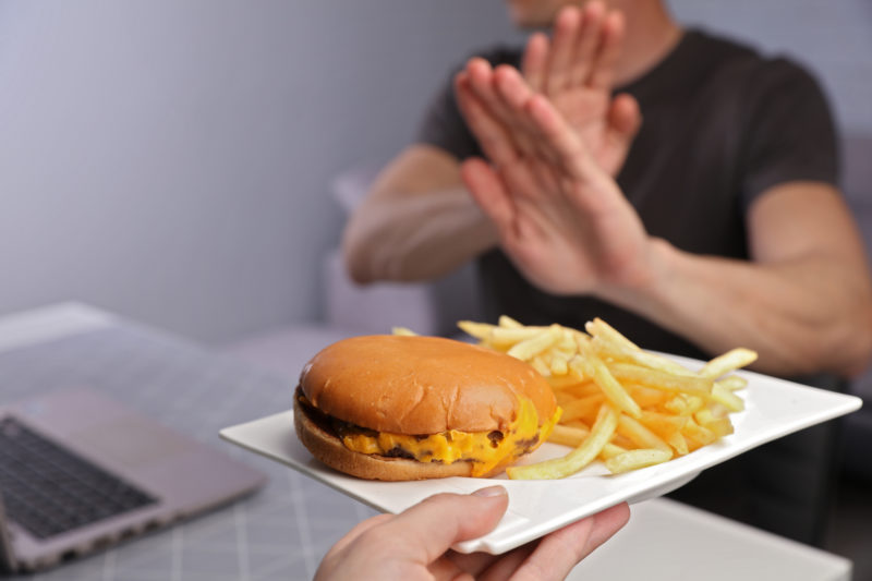 Man Saying No to High Cholesterol Junk Food. Healthy Eating. High Cholesterol is Associated with Leg Artery Disease.